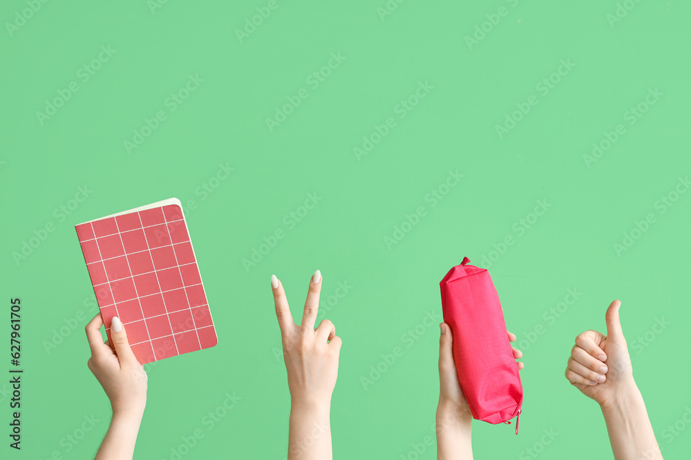 Female hands with notebook and pencil case on green background