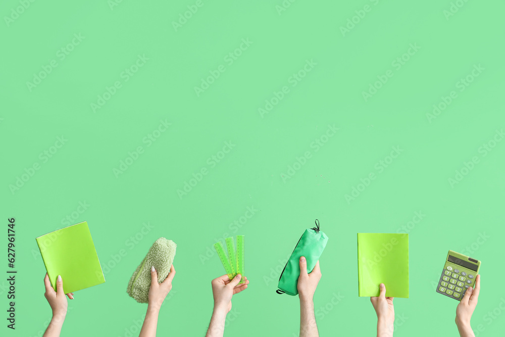 Hands with school accessories on green background