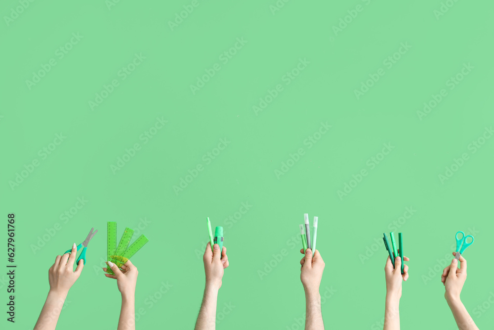 Hands with school accessories on green background