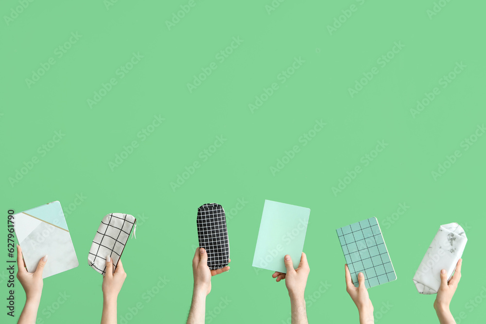 Hands with school accessories on green background