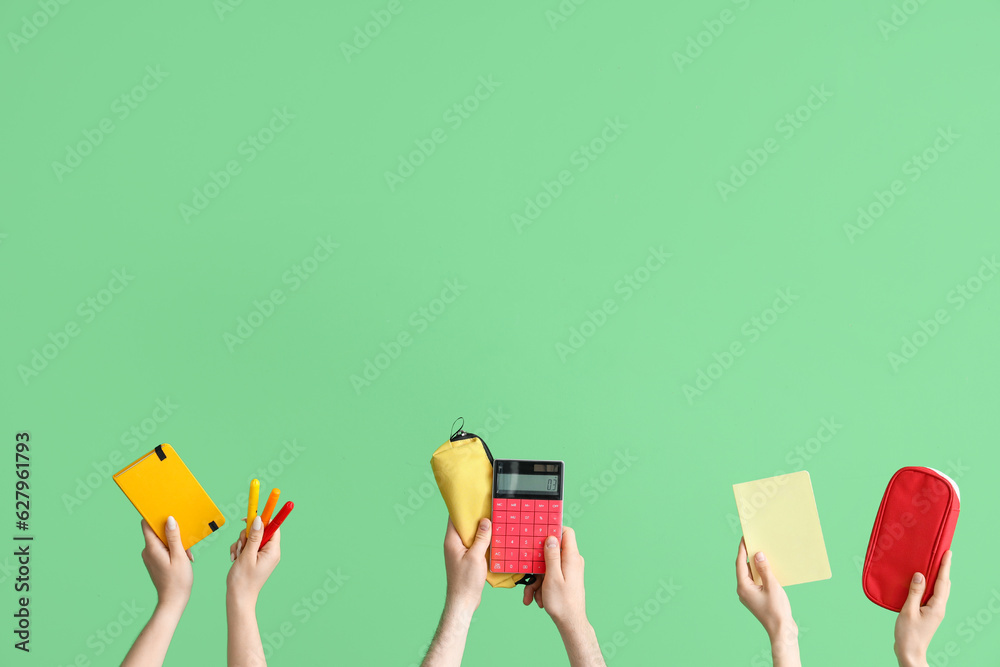 Hands with school accessories on green background