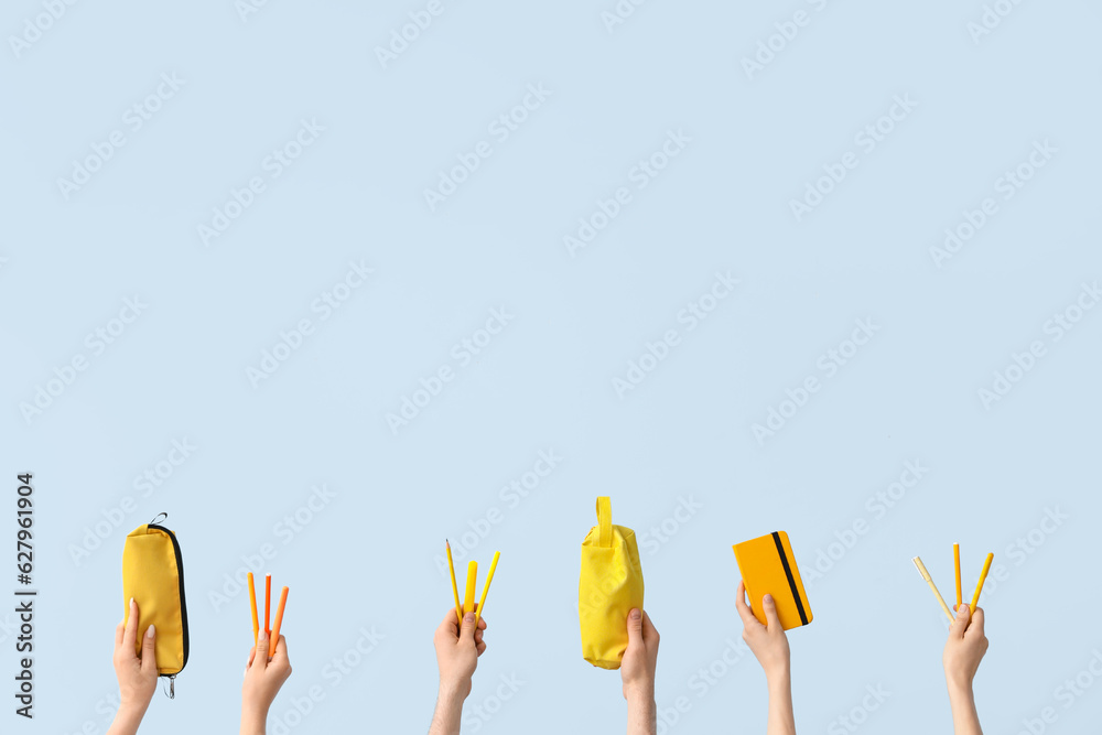 Hands with school supplies on blue background