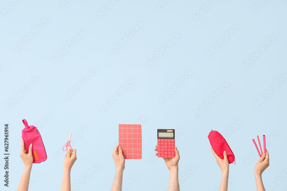 Hands with school supplies on blue background