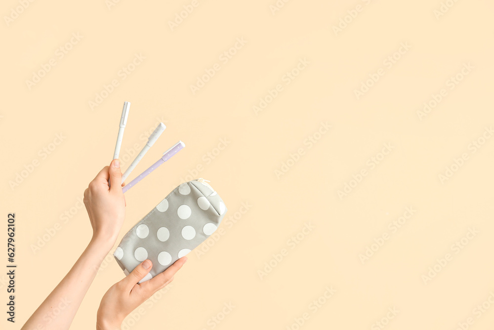 Female hands with pencil case and felt tip pens on beige background