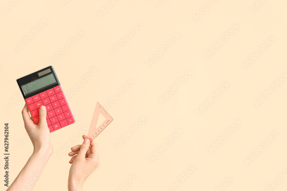 Female hands with calculator and ruler on beige background