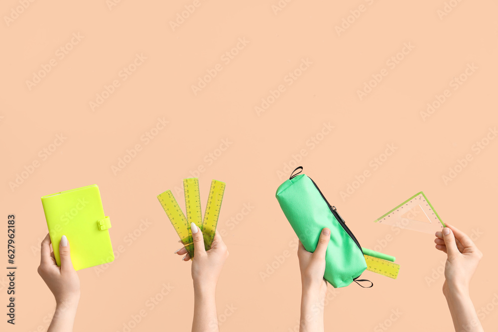 Female hands with school supplies on beige background