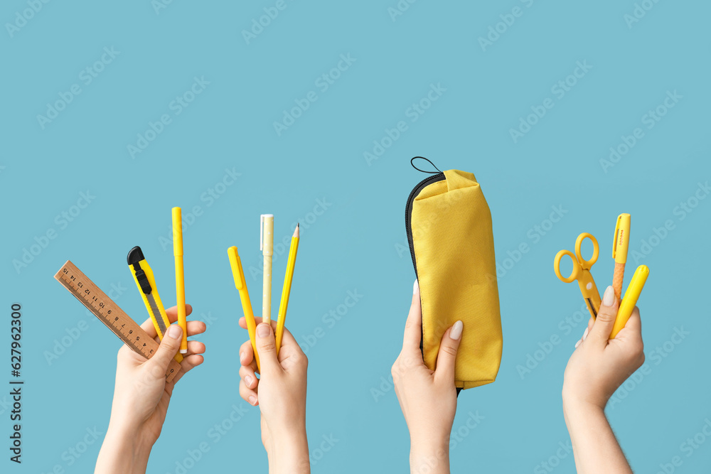 Female hands with school supplies on blue background