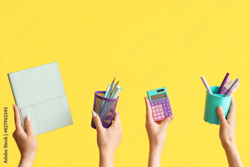 Female hands with school supplies on yellow background