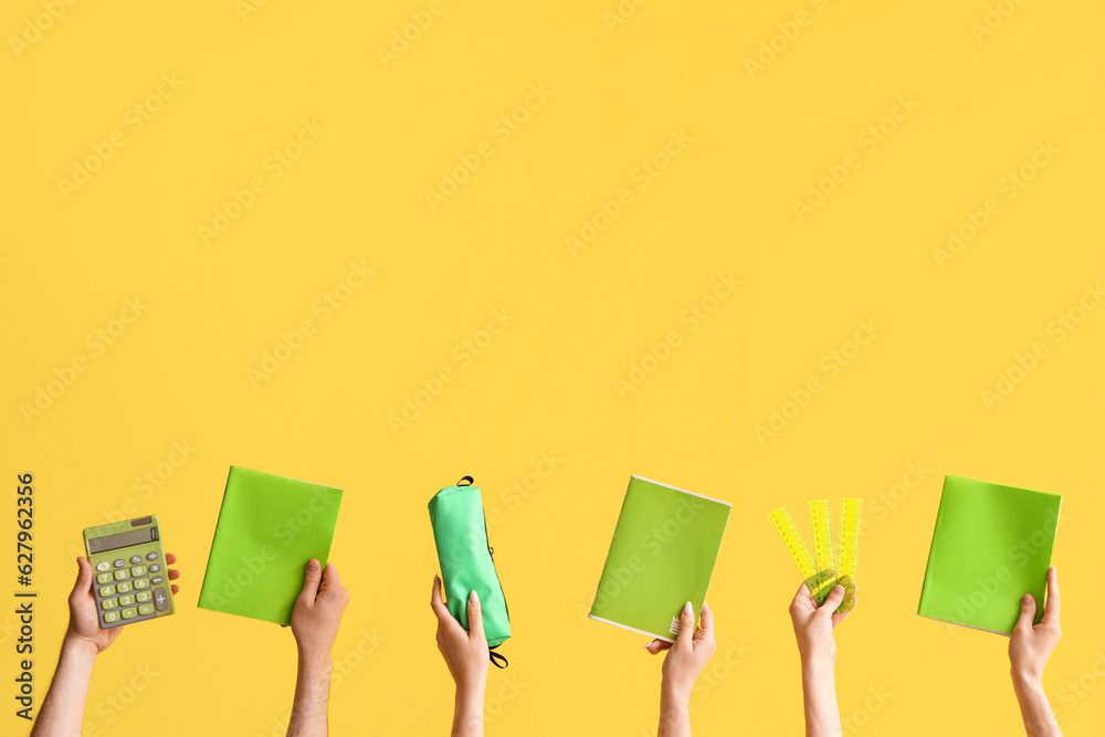 Hands with school supplies on yellow background