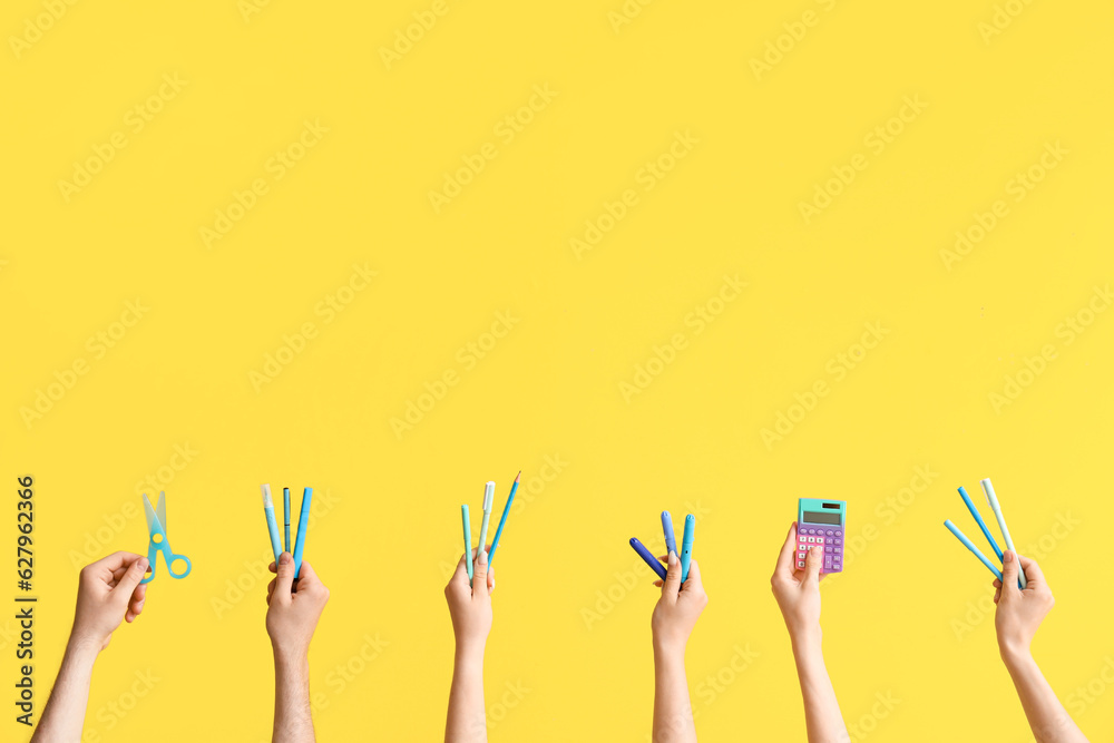 Hands with school supplies on yellow background