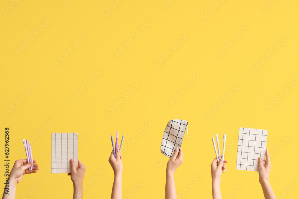 Hands with school supplies on yellow background