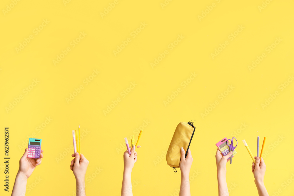 Hands with school supplies on yellow background