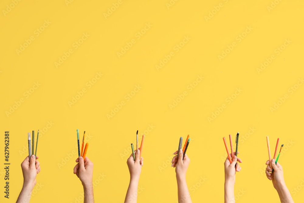 Hands with school supplies on yellow background