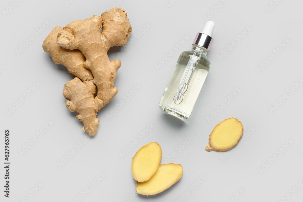 Bottle of ginger cosmetic oil on grey background