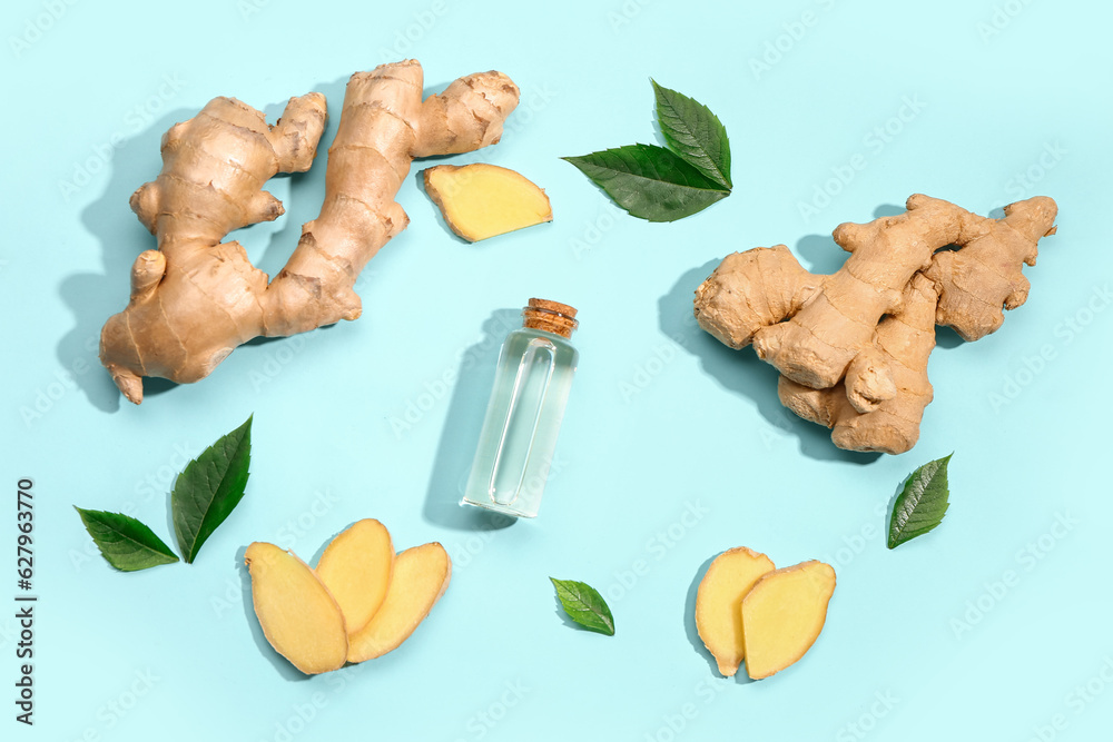 Bottle of ginger cosmetic oil and leaves on blue background