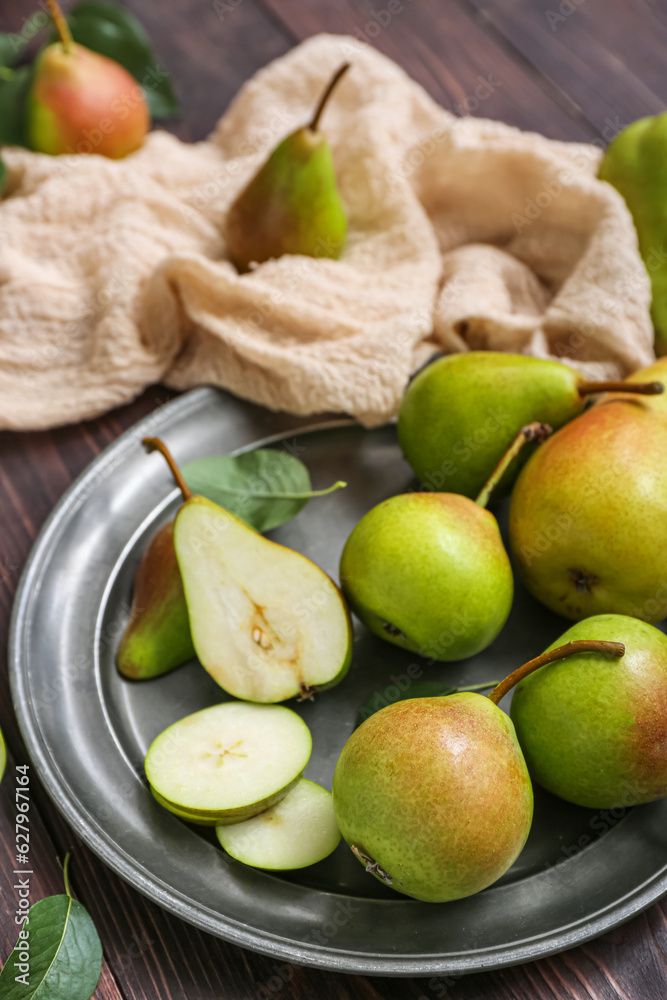 Plate with ripe pears on dark wooden table, closeup