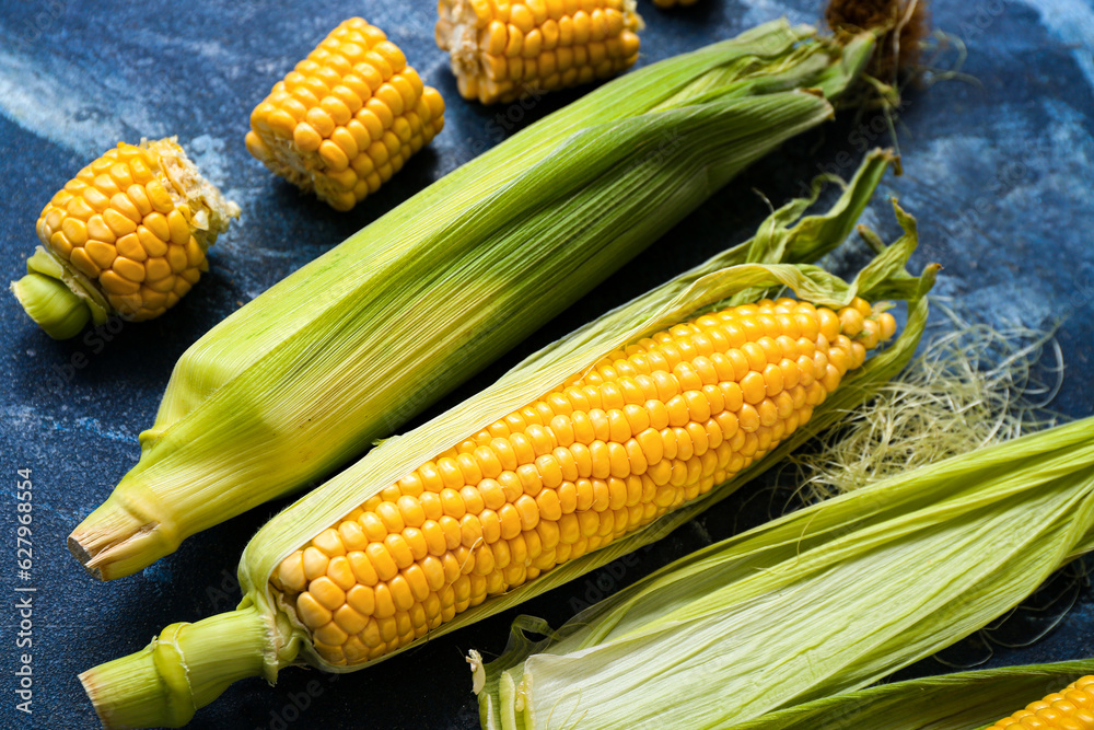 Fresh corn cobs on blue table