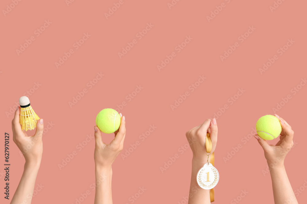 Female hands with tennis balls, shuttlecock and medal on pink background