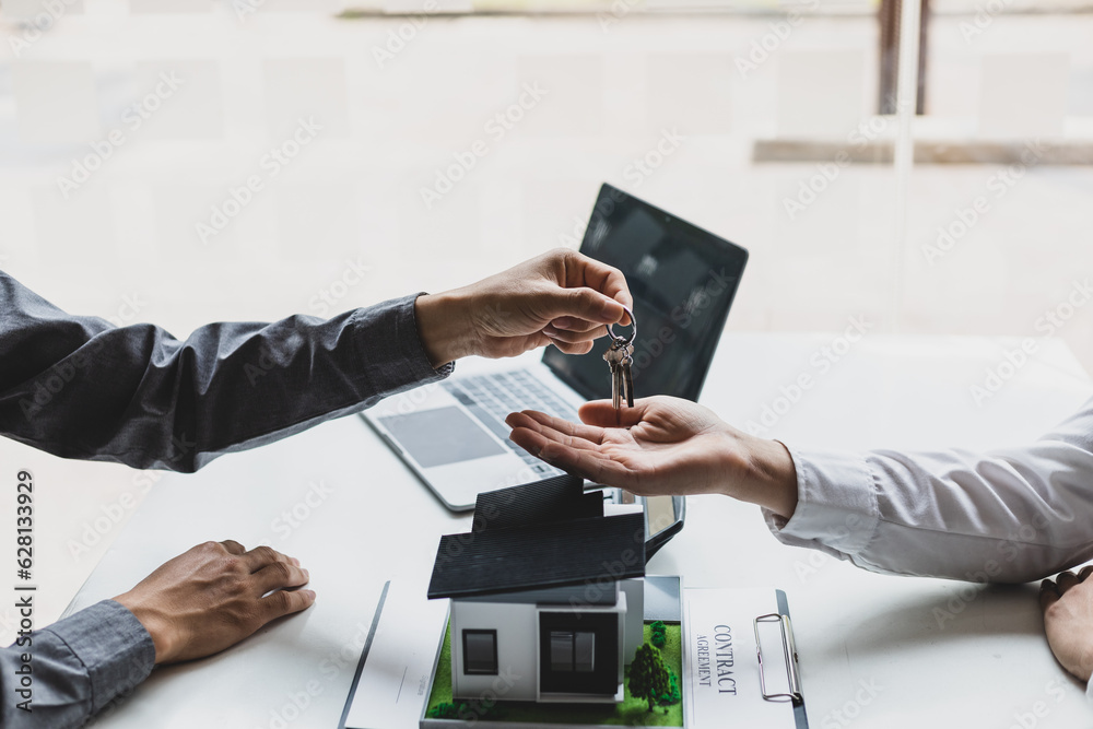 Real estate agent hands over the house keys to a homebuyer after the purchase agreement has been sig