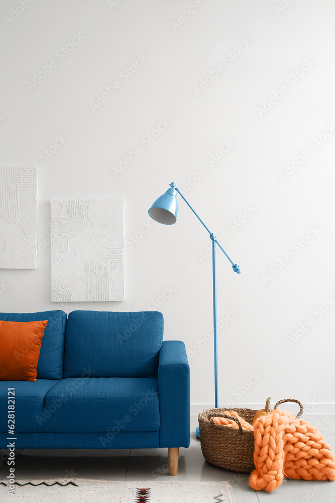 Interior of light living room with blue sofa and lamp