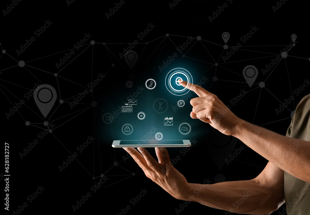 Man with tablet computer and digital icons on dark background. Concept of internet