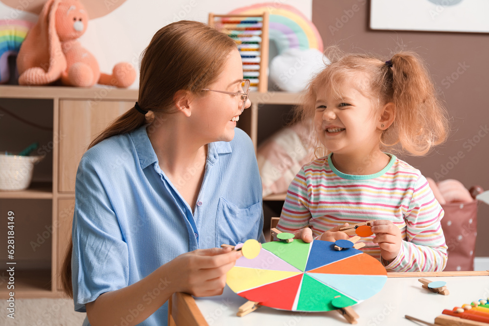 Mother and her little daughter playing matching game with clothespins at home