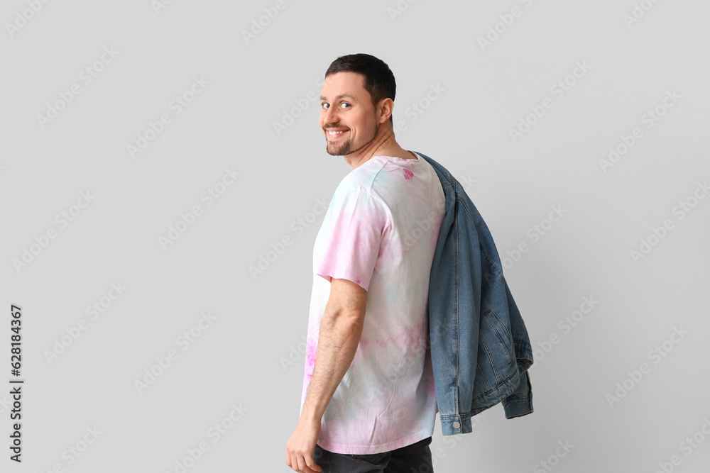 Handsome man in tie-dye t-shirt on light background