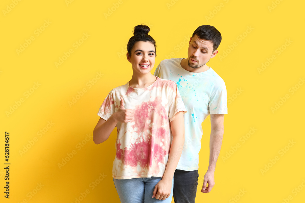 Young couple in tie-dye t-shirts on yellow background