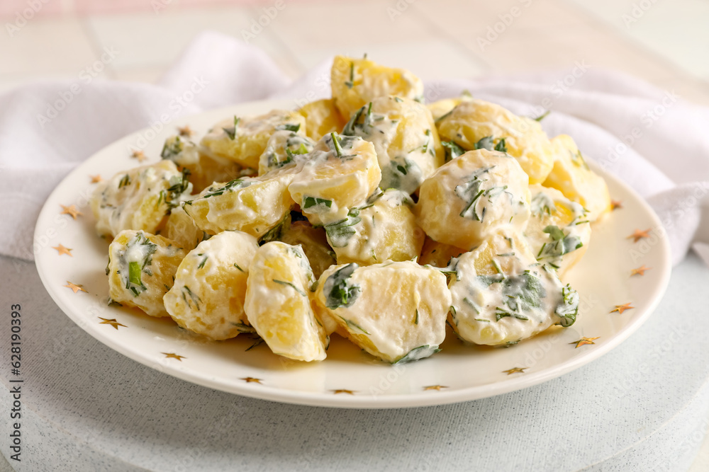 Plate of tasty Potato Salad with greens on table, closeup