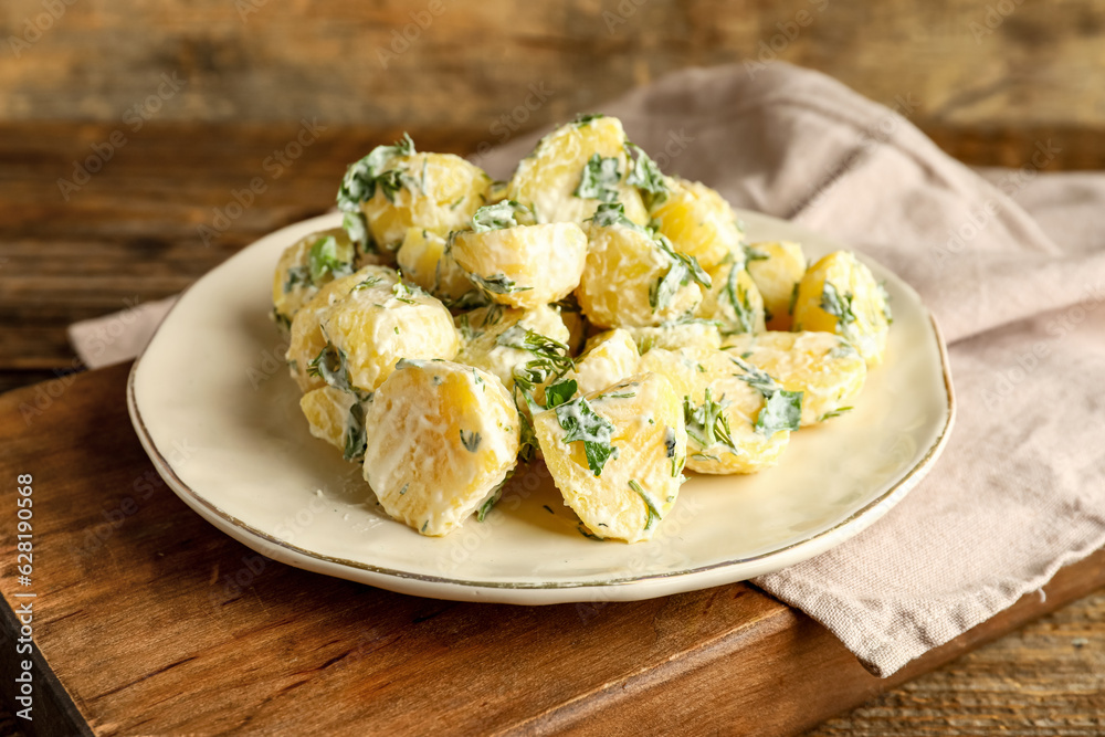 Plate of tasty Potato Salad with greens on wooden background