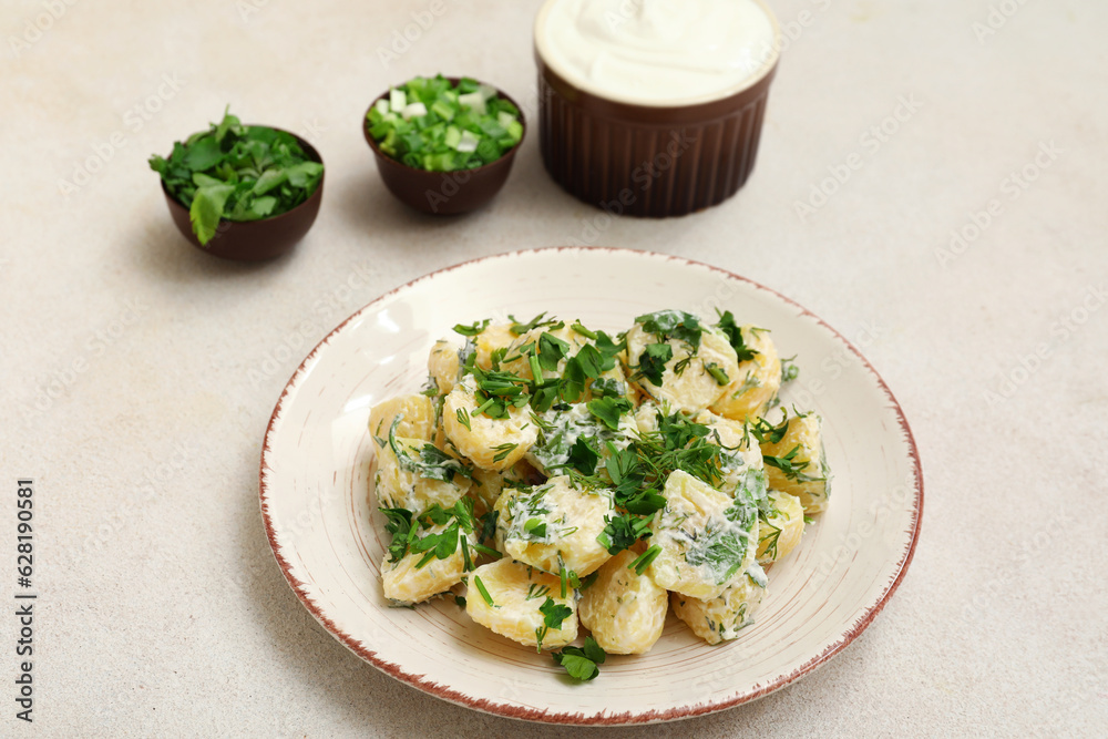 Plate of tasty Potato Salad with greens on light background