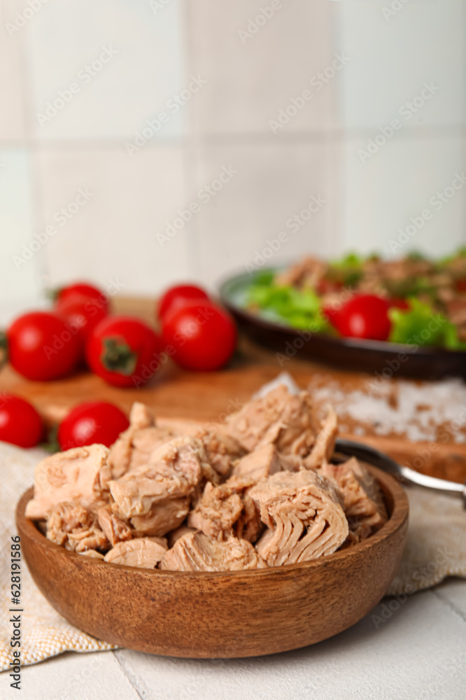 Wooden bowl with delicious canned tuna on white tiled table