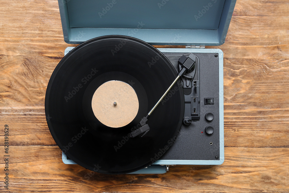 Record player with vinyl disk on wooden background