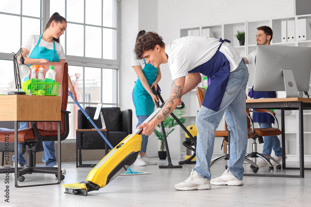 Young janitors cleaning in office