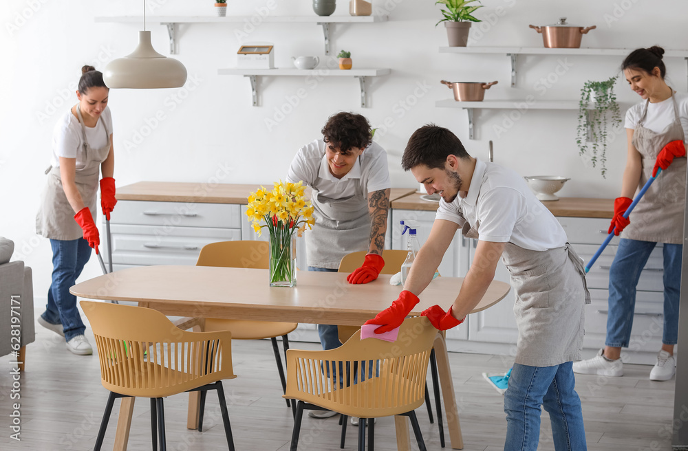 Young janitors cleaning in kitchen