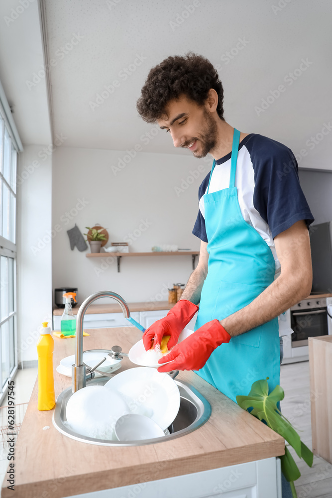 Young man washing dishes in kitchen