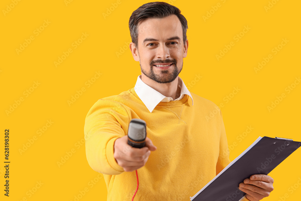 Male journalist with microphone and clipboard on yellow background