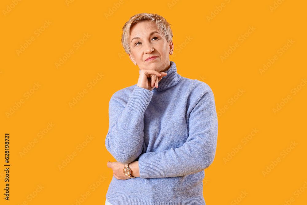 Thoughtful mature woman on yellow background