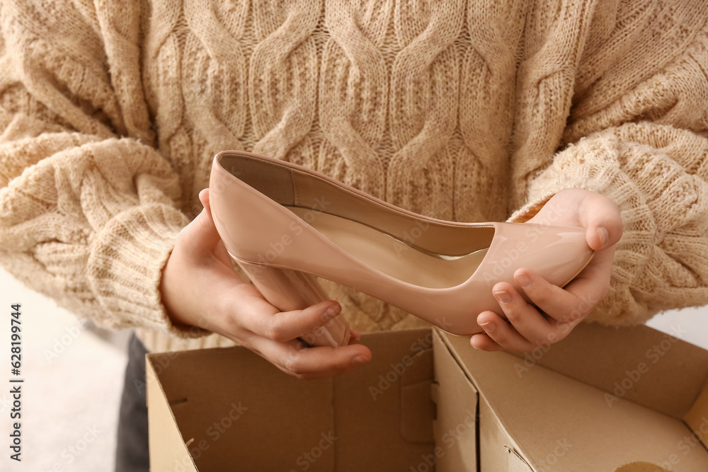 Woman taking out beige leather heels from box in room