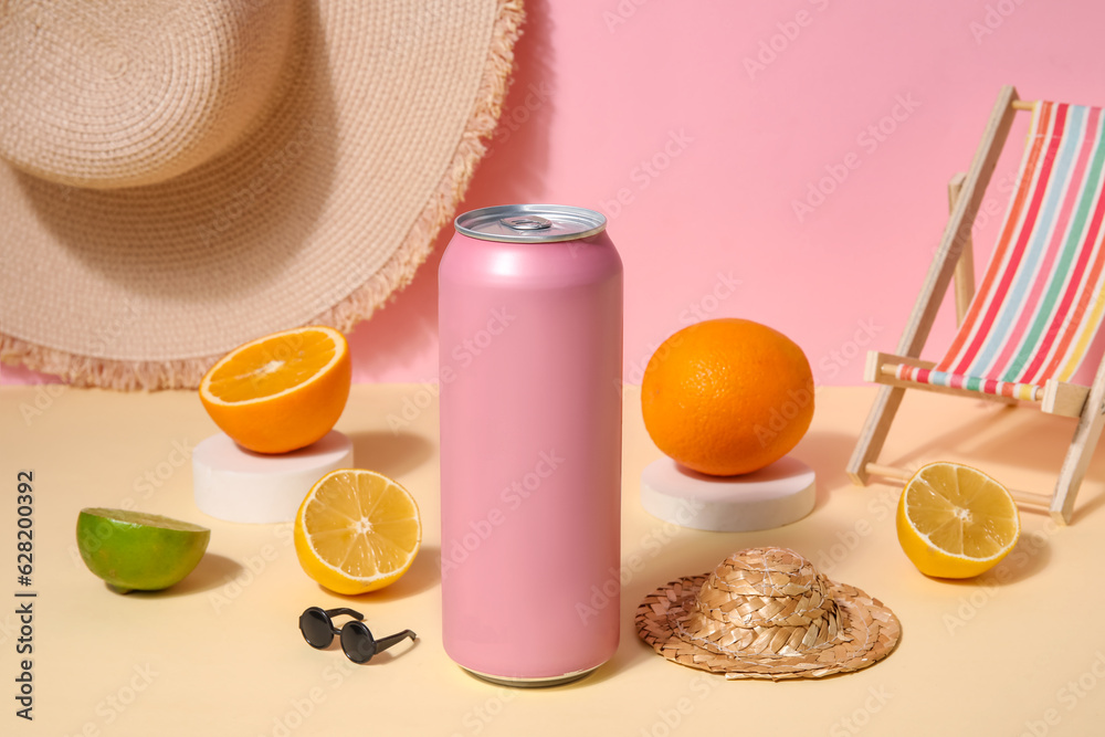 Can of soda with beach accessories and citrus fruits table near pink wall