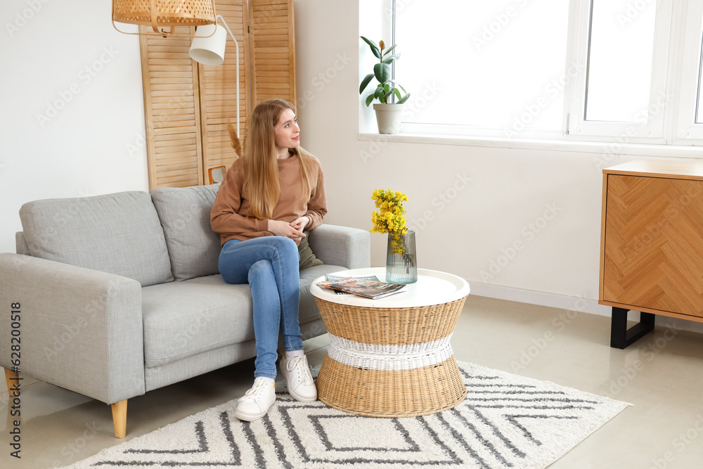 Dreaming young woman on sofa at home