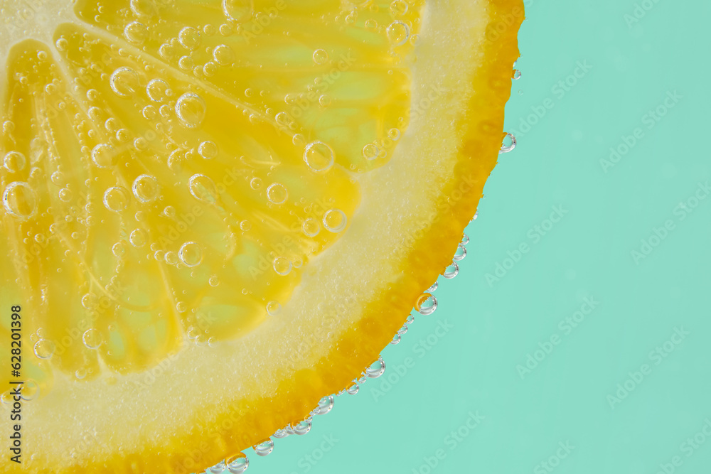 Lemon slice in water with bubbles on turquoise background