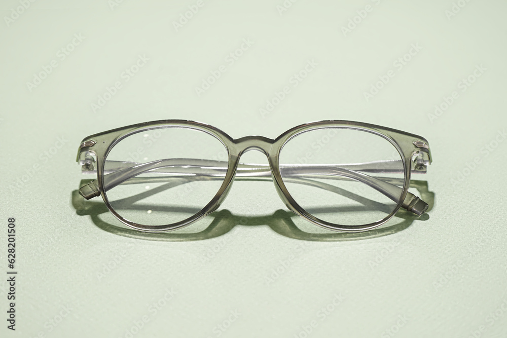 Stylish grey eyeglasses on pale green background