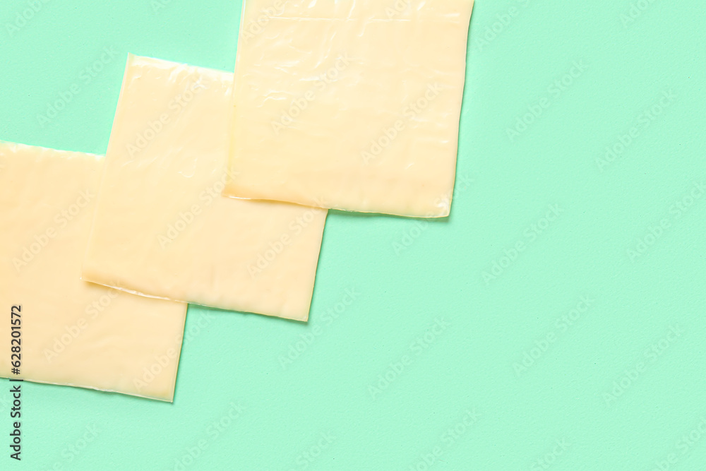 Slices of tasty processed cheese on turquoise background