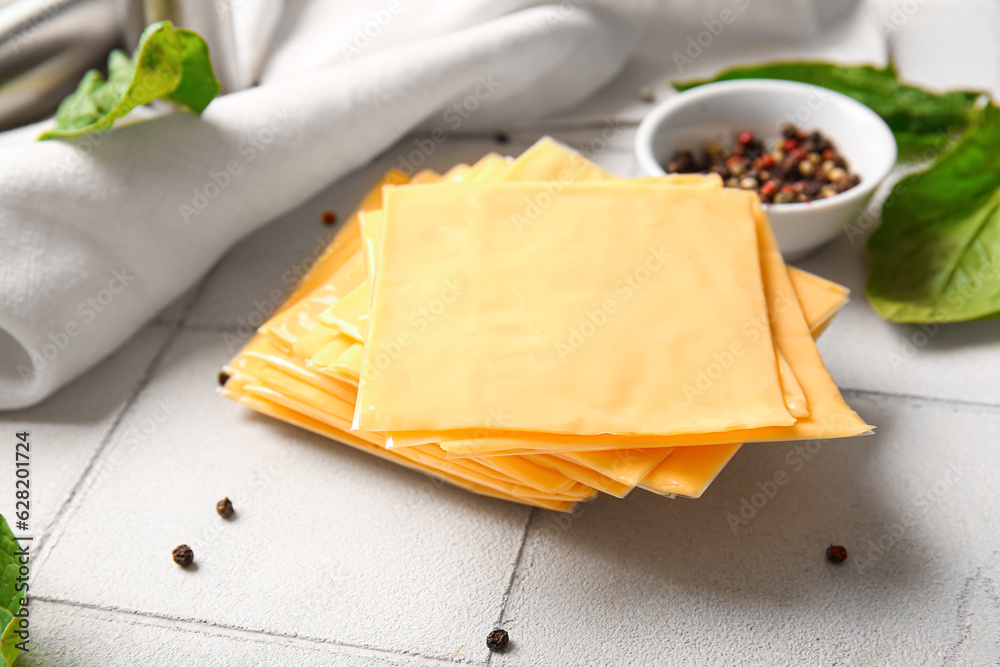 Slices of tasty processed cheese on white tile background