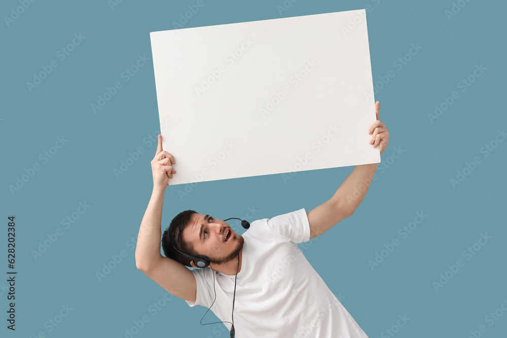 Male technical support agent with blank poster on blue background