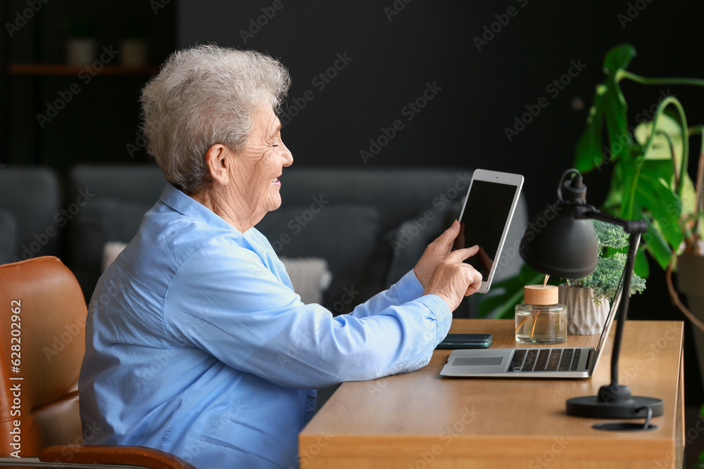 Senior woman using tablet computer at home