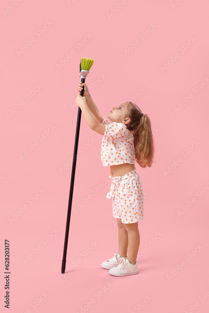 Cute little girl with broom on pink background