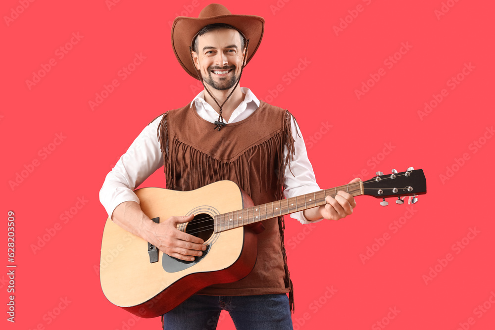 Handsome cowboy playing guitar on red background