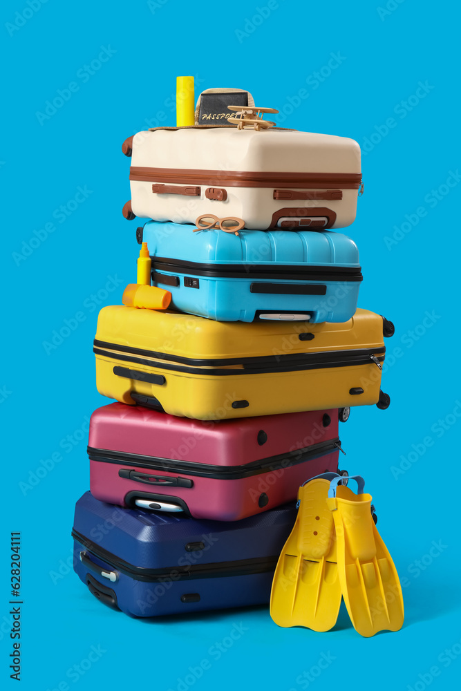 Suitcases with beach accessories on blue background